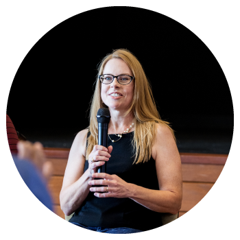 personne tenant un micro et partageant son histoire dans ce qui semble être un auditorium.